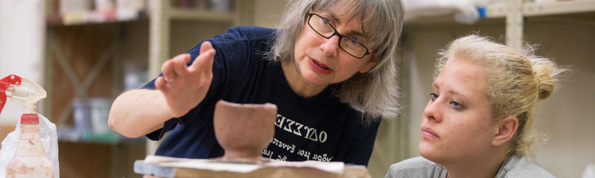 A GVSU student and faculty member working on pottery.